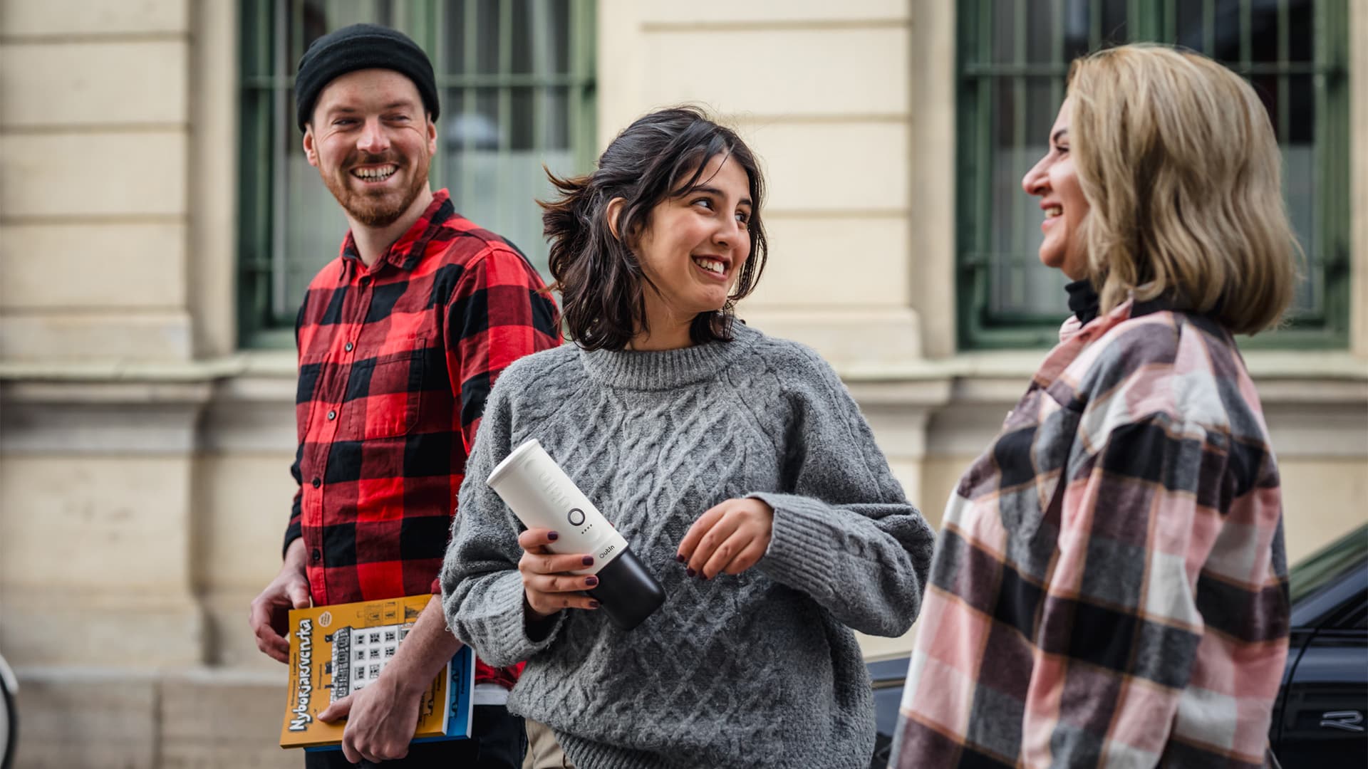 Friends smiling outdoors, with one holding the sleek, portable Outin Portable Espresso Machine, ready for coffee on the go