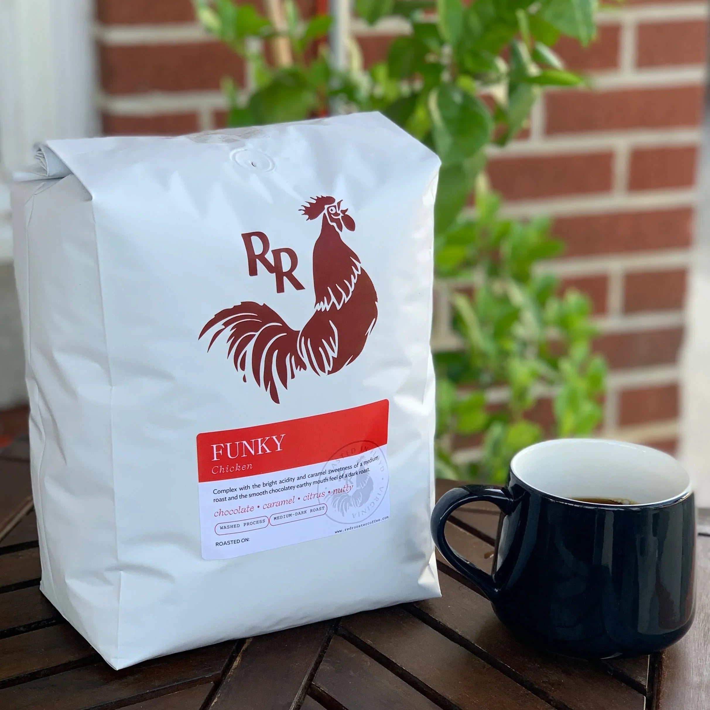 Red Rooster Funky Chicken coffee bag & mug on wood table. Medium-dark roast, pecan praline, lemon-lime, milk chocolate truffle.