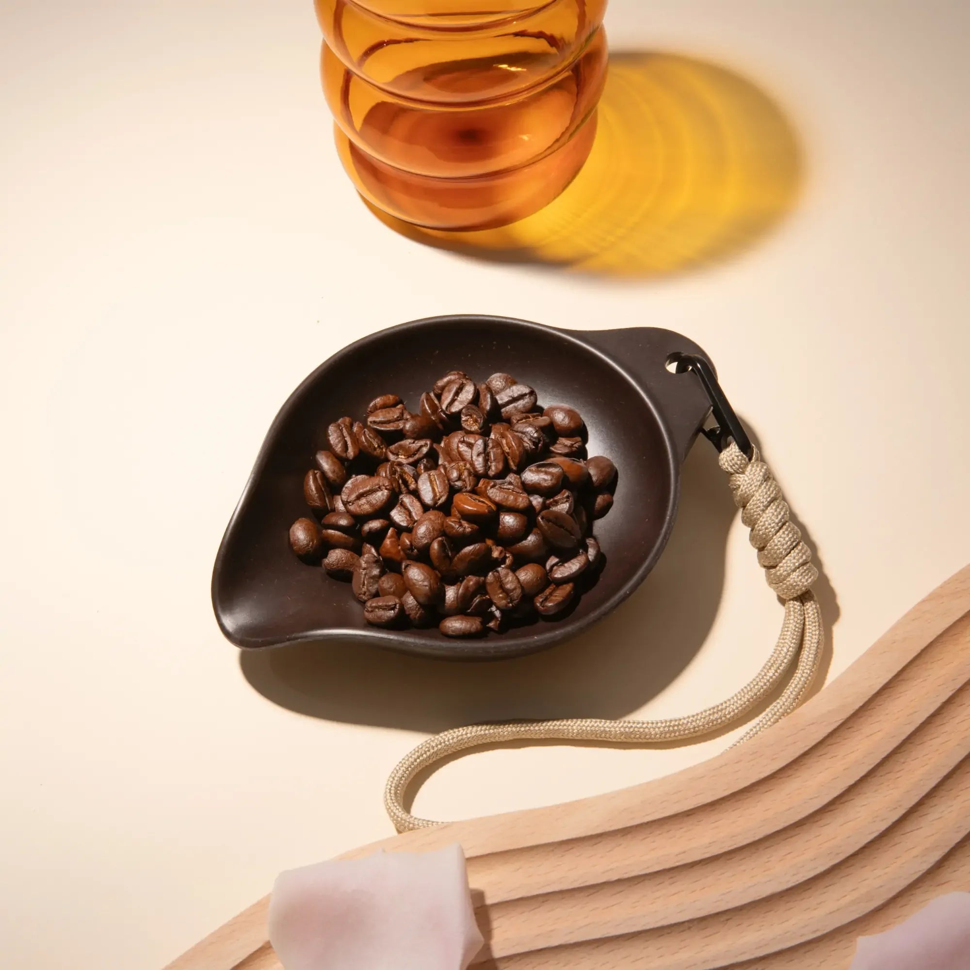 OutIn Rebrew Bean Tray, dark brown, drop-shape, with coffee beans and braided lanyard.