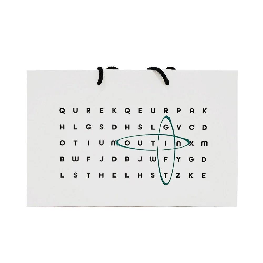 White gift bag with word search puzzle and green oval logo, black rope handles. Ideal for portable espresso machines.