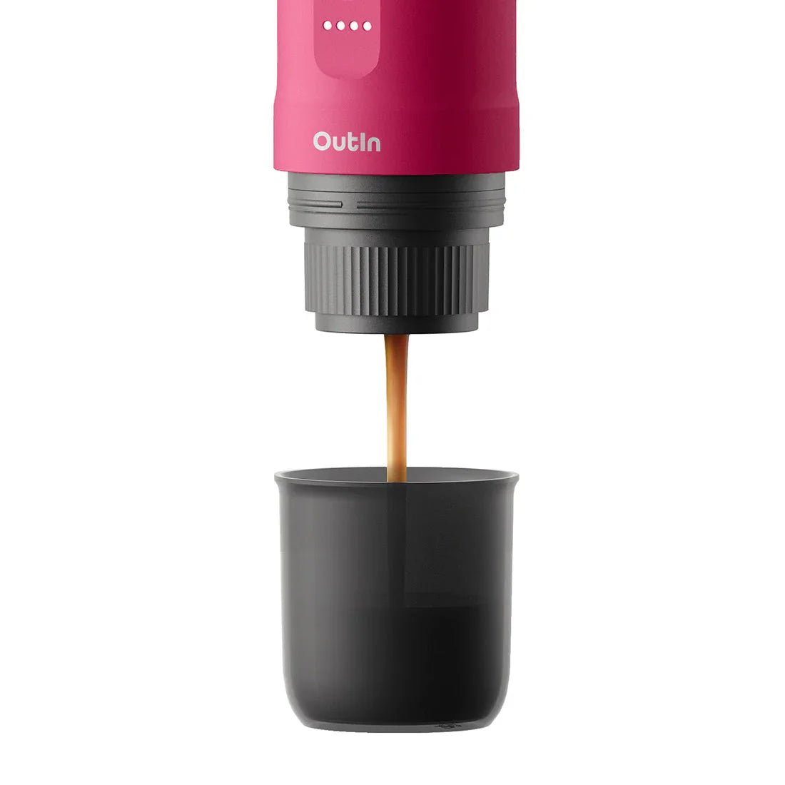 Fuchsia Nano portable espresso machine brewing rich espresso into a dark grey cup, showcasing brewing process.
