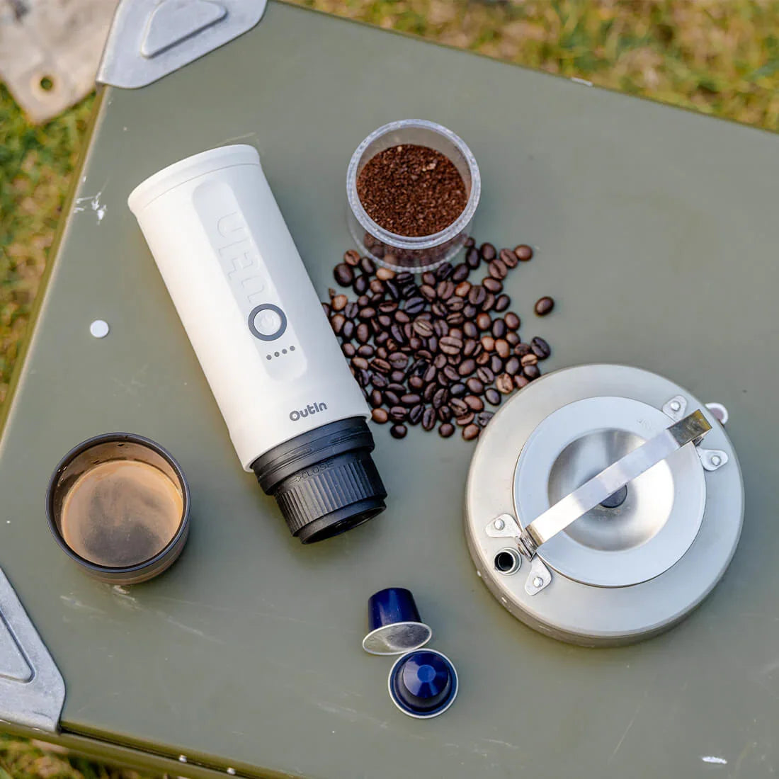 Pearl white Nano portable espresso machine with coffee beans, grounds, capsules, cup, and kettle.