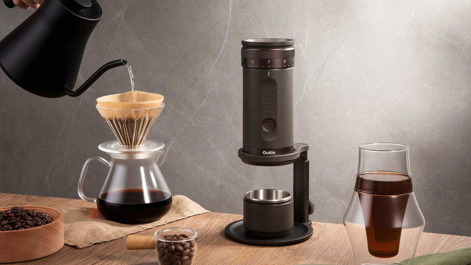 Manual pour over coffee brewing setup with Outin grinder, glass carafe and fresh ground coffee on table, specialty coffee process