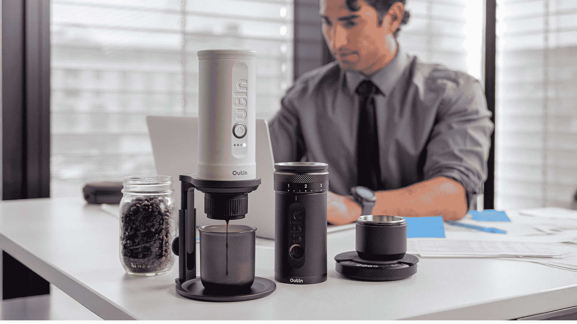 Office worker brewing espresso with Outin Nano at desk