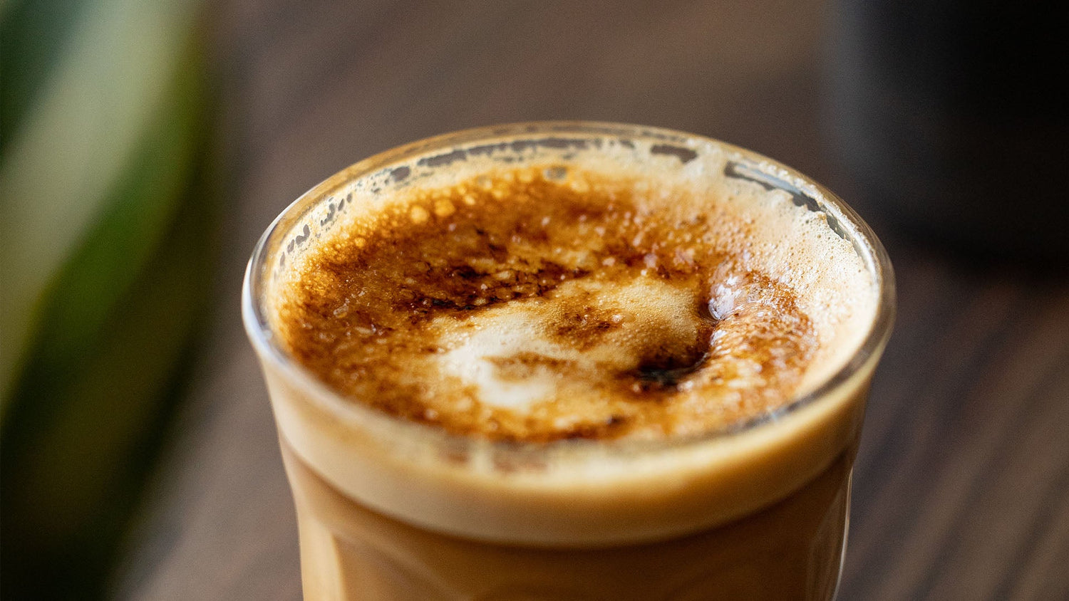 Close-up of freshly brewed coffee in a glass showing rich golden-brown crema with tiny bubbles forming on top, providing the perfect base for latte art designs.