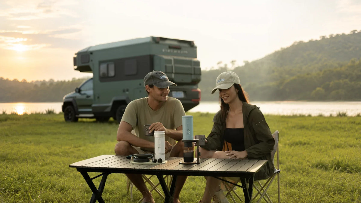 Travelers using OutIn portable coffee makers at a lakeside campsite