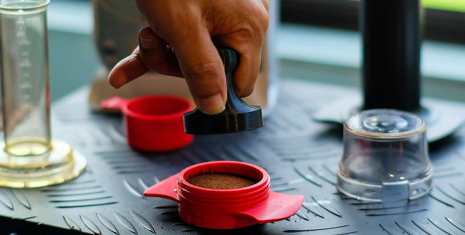 Tamping espresso grounds in red portafilter