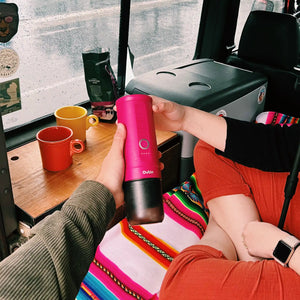 Person holding fuchsia Nano Portable Espresso Machine inside a vehicle.