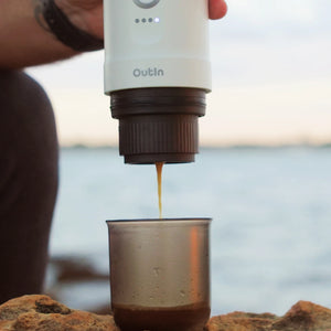 Espresso pouring from Nano Portable Espresso Machine into coffee cup outdoors.