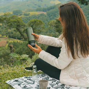 Woman enjoying forest green Nano Portable Espresso Machine in nature.