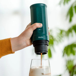 Teal Outin Nano Espresso Machine pouring coffee into a glass, emphasizing portability.