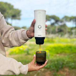 Hand pouring espresso from Pearl White Nano Portable Espresso Machine into a coffee cup.