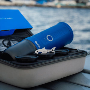 Ocean Blue thermos and espresso accessories in storage case by the water.