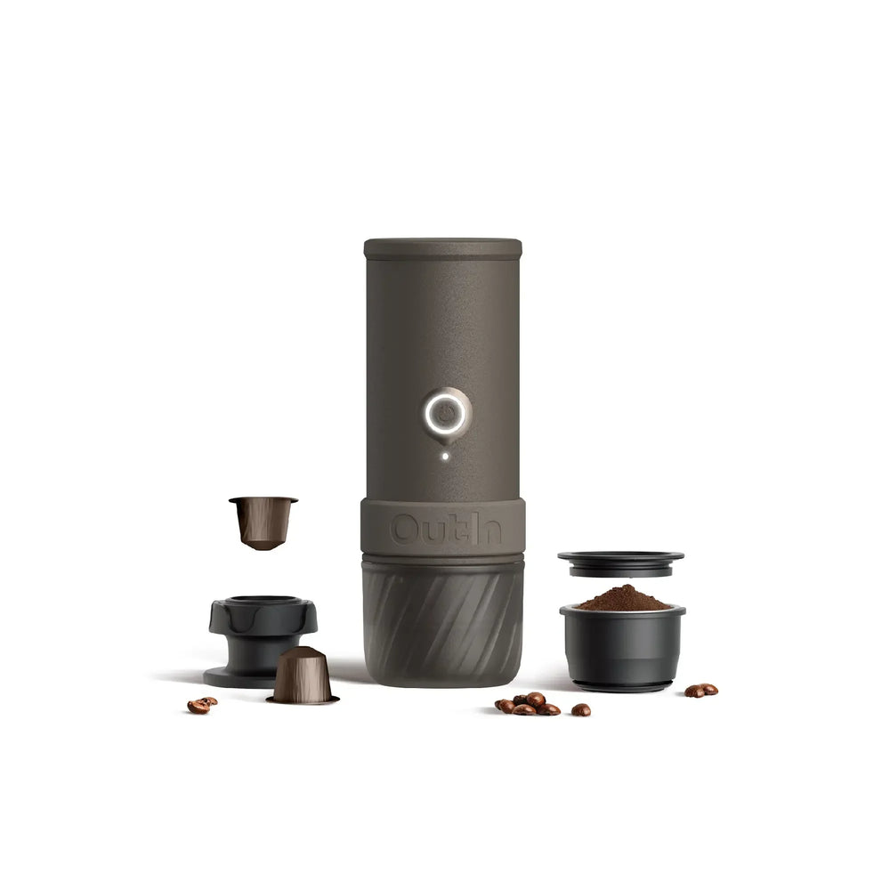 Dark gray OutIn portable espresso machine with coffee pods, grounds, tamper, and beans. Shows product and components.