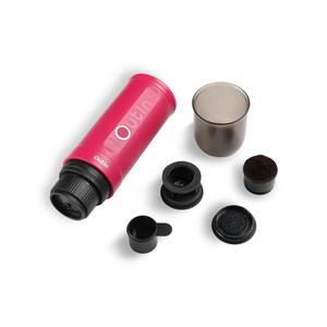 Fuchsia Nano Portable Espresso Machine with brewing accessories laid out around it.